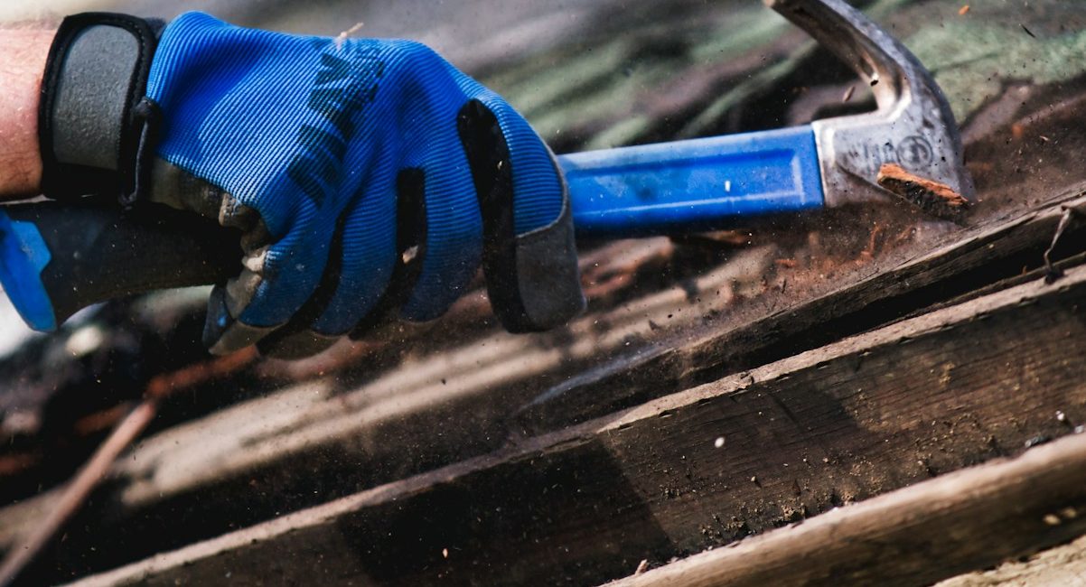 a person wearing blue gloves and holding a hammer