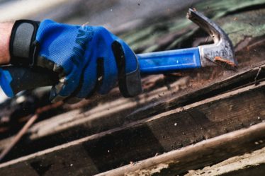 a person wearing blue gloves and holding a hammer